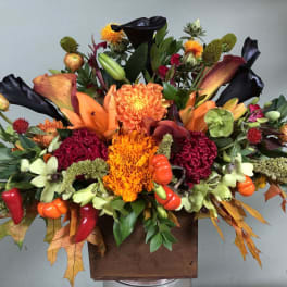 Autumn floral arrangement with orange and burgundy blooms in a wooden box