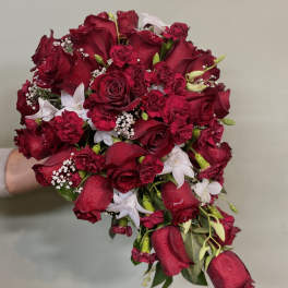 Handheld bouquet of red roses with white accent flowers