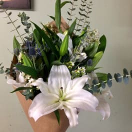 White lilies and blue thistle in brown paper wrap