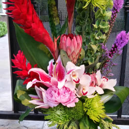 Tall tropical arrangement with red, pink, white, and green flowers in a vase