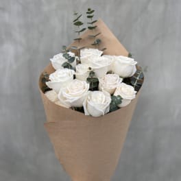 Bouquet of white roses wrapped in brown paper with eucalyptus