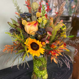 Autumn bouquet with a sunflower and rose in a glass vase