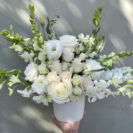 White roses and orchids in a white vase