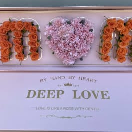 Pink floral gift box with orange roses and a heart-shaped cluster of pink carnations