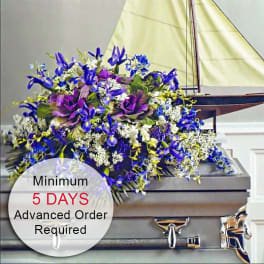 Purple and blue casket spray with white accents displayed on a gray casket