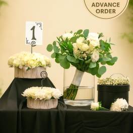 White rose wedding bouquet with matching centerpieces and floral crown on a black-draped table