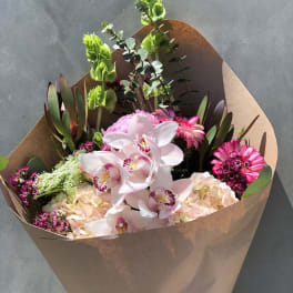 Bouquet of pink orchids and mixed flowers wrapped in brown paper