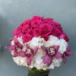 Pink roses and white hydrangeas with magenta orchids in a glass vase