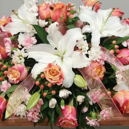 Large floral casket spray with white lilies, pink roses, and ribbon accents