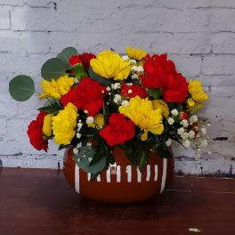 Red and yellow flower arrangement in a brown ceramic vase