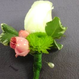 Boutonniere with a white rose, pink rosebud, and green accent flower
