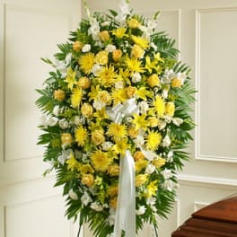 Standing funeral spray of yellow and white flowers on an easel