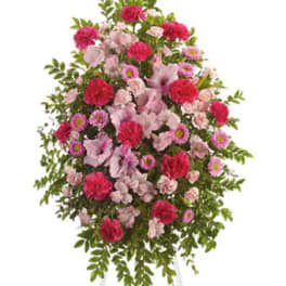 Standing spray of pink and red flowers on a white easel