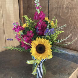 Sunflower bouquet with bright pink and purple flowers in a glass vase