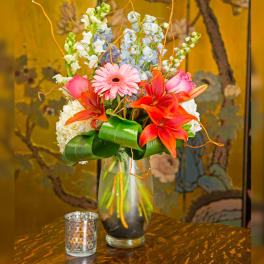 Colorful mixed flower arrangement in a glass vase with a candle holder