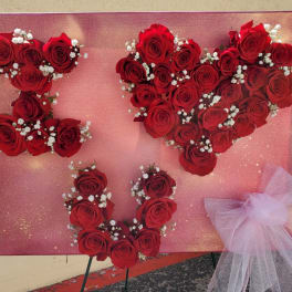 Red rose heart display on a pink board with a tulle bow
