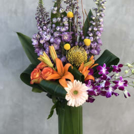 Tall mixed bouquet with orange lilies, purple orchids, and a pale gerbera daisy
