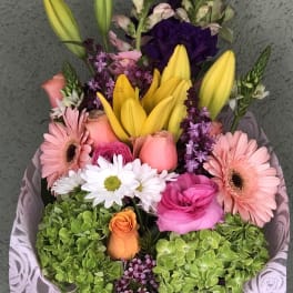 Bouquet of lilies, roses, gerbera daisies, and hydrangeas in pink wrap