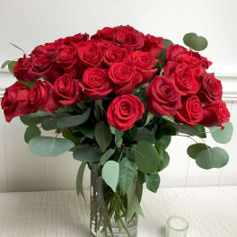 Bouquet of red roses in a clear glass vase with eucalyptus