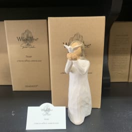 White angel figurine in front of cardboard gift boxes