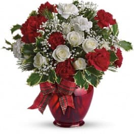 Red and white floral arrangement in a red vase with a plaid ribbon