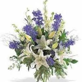 White lilies and purple flowers in a clear glass vase