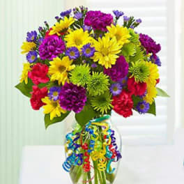 Colorful mixed bouquet in a clear glass vase with curly ribbon