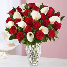 Red roses and white calla lilies in a clear glass vase