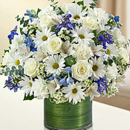 White roses and daisies with blue flowers in a green vase