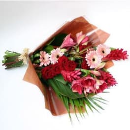 Bouquet of red and pink flowers wrapped in brown paper