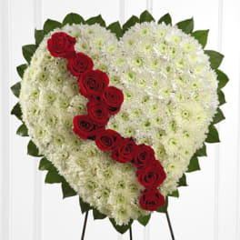 Heart-shaped floral tribute with white flowers and a diagonal line of red roses