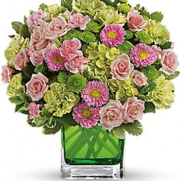 Pink roses and green carnations in a square glass vase