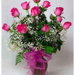 Pink roses in a vase with baby's breath and a pink ribbon