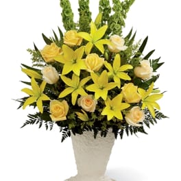 Yellow lilies and cream roses in a white pedestal vase