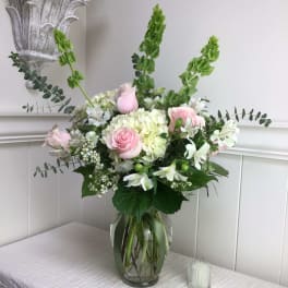 Pink roses and white flowers arranged in a glass vase