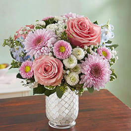 Pink roses and daisies arranged in a clear glass vase