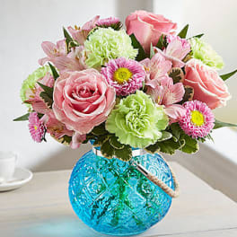 Pink roses and mixed flowers in a blue glass vase