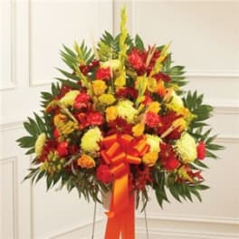 Large standing floral spray with red, yellow, and orange flowers on an easel
