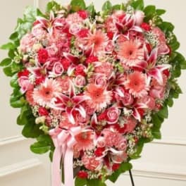 Heart-shaped bouquet of pink and red flowers with a ribbon
