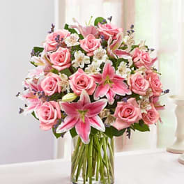 Pink roses and lilies arranged in a clear glass vase