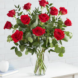Red roses in a clear glass vase with mixed greenery