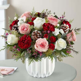 Pink and white roses with red carnations in a white vase