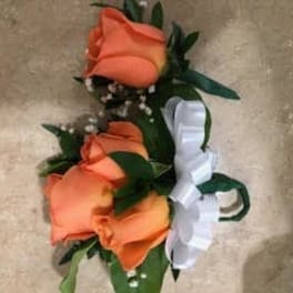 Orange rose corsage with white ribbon on a beige background