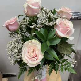 Bouquet of pale pink roses with white filler flowers in a pink vase