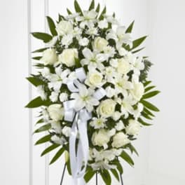 White funeral spray with lilies and roses on a stand