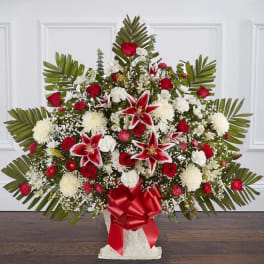 Large red and white floral spray with lilies and roses in a white vase