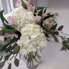 White hydrangeas and pink lilies in a clear glass vase