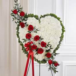 Heart-shaped floral spray with white blooms and red roses on an easel
