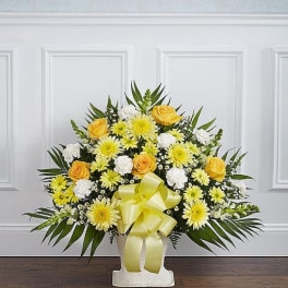 Yellow and white floral arrangement with a ribbon in a white vase