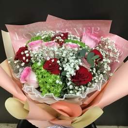 Bouquet of red and pink roses with white baby's breath in pastel wrapping
